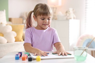 Beyaz masalarda avuç içleri çizen sevimli küçük kız.