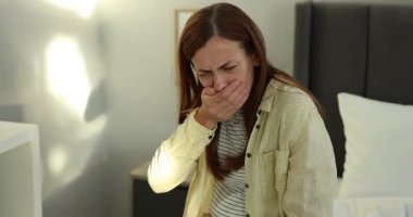 Evde yatağında mide bulantısı çeken hamile bir kadın.