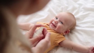 Anne evde bebeğinin yüzüne krem sürüyor, yakın plan.