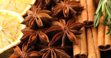 Farklı baharatlar, kuru portakal dilimleri, taze biberiye ve sıcak şarap için kızılcık, yakın plan. Kamera sağa hareket ediyor