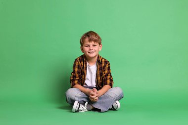 Yeşil arka planda yakışıklı bir çocuğun portresi.