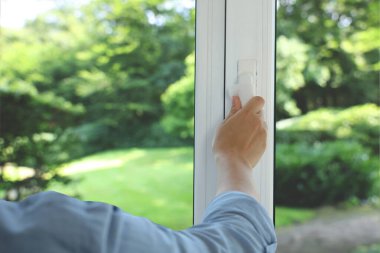 Pencereyi temizleyen kadın, yakın çekim. Yeşil bahçe, camdan manzara