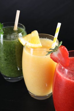 Farklı lezzetli içecekler ve siyah ahşap masada malzemeler var.