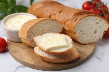 Beyaz mermer masada tereyağlı, fesleğenli ve domatesli baget kes.