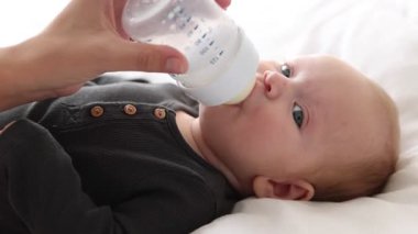 Anne bebeğini şişeyle besliyor.