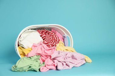 Açık mavi arkaplanda giysileri olan çamaşır sepeti, metin için boşluk