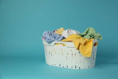 Açık mavi arkaplanda giysileri olan çamaşır sepeti, metin için boşluk