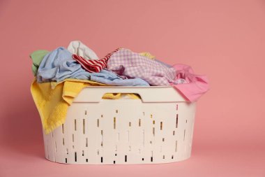 Pembe arka planda giysileri olan çamaşır sepeti