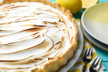Turkuaz ahşap masada servis edilen lezzetli limonlu turta, yakın plan.