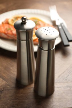 Ahşap masada servis edilen tuzluk ve ızgara somon, yakın plan.