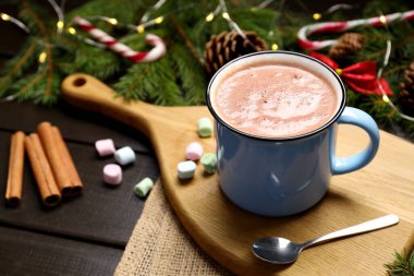 Bardakta sıcak kakao, marşmelov ve karanlık ahşap masada Noel süsü, yakın plan.
