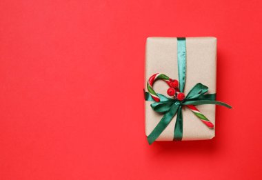 Kırmızı arka planda baston şekerle süslenmiş Noel hediyesi, üst manzara. Metin için boşluk