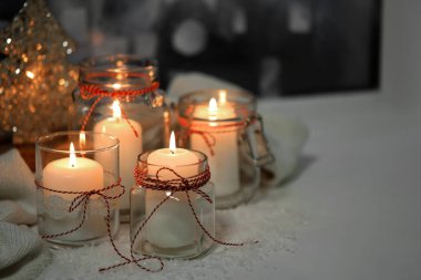 DIY Noel fenerleri. Cam kavanozlarda mum yakmak ve pencerenin pervazında yapay kar, yakın plan. Metin için boşluk
