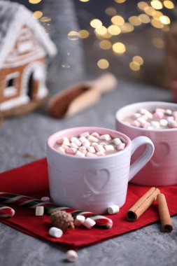 Gri masada lokum, tarçın ve Noel dekoru olan lezzetli kakao bulanık ışıklara karşı, yakın plan.