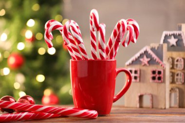 Kupada baston şekerler ve ahşap masada bulanık ışıklara karşı Noel süsü.