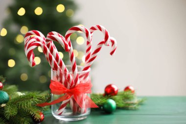 Cam çubuk şekerler ve yeşil ahşap masada bulanık ışıklara karşı Noel süsü. Metin için boşluk