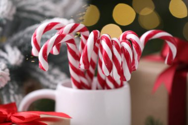 Bardaktaki şeker kamışları ve bulanık ışıklara karşı Noel süsü, yakın plan.