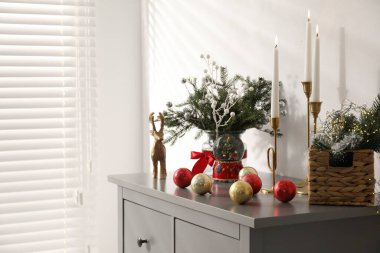 Beyaz duvarın yanındaki gri dolapta farklı bir Noel dekoru var.