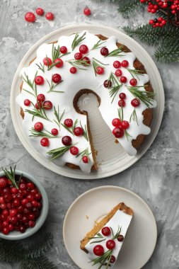 Lezzetli bir Noel pastası, kremalı, kızılcıklı, biberiyeli ve köknar ağacı dallı gri desenli masa, düz uzanmış