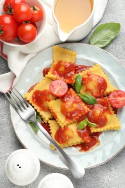Gri masada servis edilen domates soslu ve fesleğenli lezzetli ravioli.