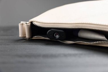 Çantanın içinde gizli casus kamerası, ahşap masanın üstünde, yakın plan.