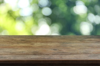 Dışarıdaki boş ahşap masa. Arka planda bulanık yeşillik. Tasarım için boşluk