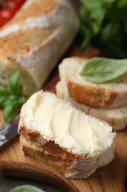 Tahta masada tereyağlı, fesleğenli ve bıçaklı baget dilimleri, yakın plan.