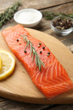 Bir parça somon fileto, baharat ve limon ahşap masada, yakın plan.