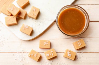Lezzetli şekerler, hafif ahşap masada tuz ve karamel sosu.