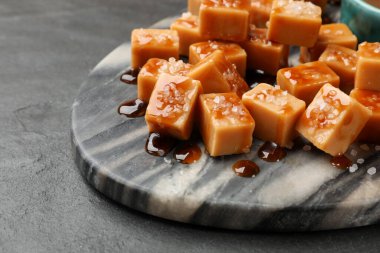 Koyu dokulu masada tuz ve karamel soslu lezzetli şekerler, yakın plan.