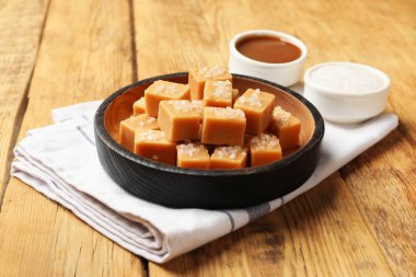 Ahşap masada tuz ve karamel soslu lezzetli şekerler, yakın plan.