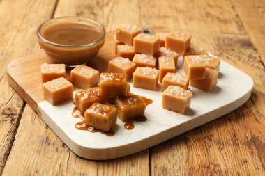 Ahşap masada tuz ve karamel soslu lezzetli şekerler, yakın plan.