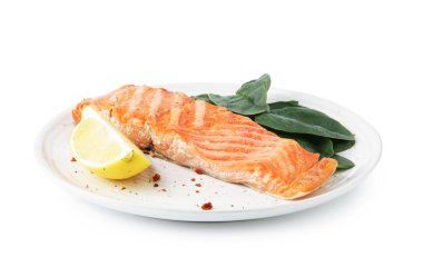 Lezzetli ızgara somon, limon dilimi ve beyaz üzerine izole edilmiş ıspanak.