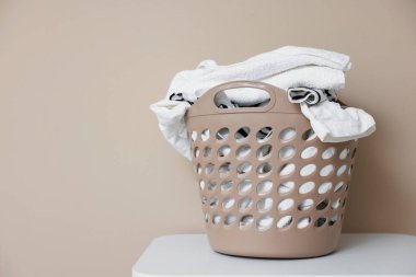 İçerideki bej duvarın yanında çamaşır sepetli plastik sepet. Mesaj için yer var.