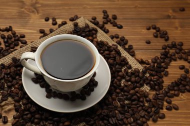 Aromatik kahve fincanda, fasulye de ahşap masada, yakın plan. Metin için boşluk