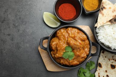 Lezzetli tavuk tikka masala, pilav, kişniş, kireç, lavaş ve baharatlar gri desenli masa, düz yatak. Metin için boşluk