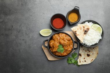 Lezzetli tavuk tikka masala, pilav, kişniş, kireç, lavaş ve baharatlar gri desenli masa, düz yatak. Metin için boşluk