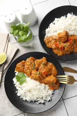 Hafif fayanslı masada servis edilen pirinçli tavuk tikka masala.