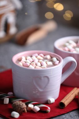 Gri masada lokum, tarçın ve Noel dekoru olan lezzetli kakao bulanık ışıklara karşı, yakın plan.