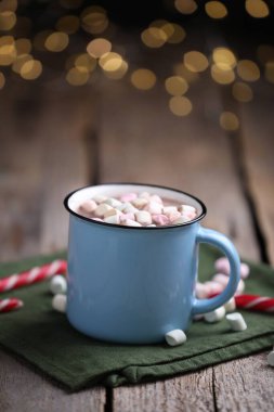 Ahşap masada lokum ve şeker kamışlı lezzetli kakao bulanık Noel ışıklarına karşı, yakın plan. Metin için boşluk