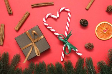 Kırmızı arka planda şeker kamışlı düz kompozisyon. Noel hediyesi