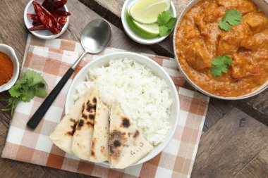 Lezzetli tavuk tikka masala, pilav, kişniş, kireç, lavaş ve baharatlar ahşap masada, düz yatıyordu.