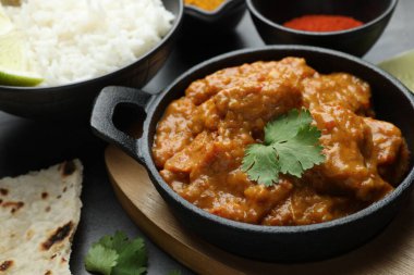 Lezzetli tavuk tikka masala, kişniş, lavaş, pirinç ve kırmızı biber tozu gri masada, yakın plan.