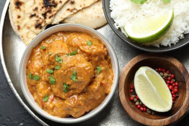 Lezzetli tavuk tikka masala, lavaş, kişniş, pirinç, limon ve biberler koyu dokulu masa, üst manzara