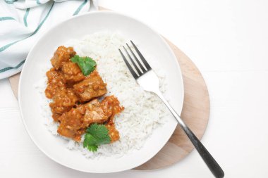 Pirinçli tavuk tikka masala, kişniş ve çatal beyaz ahşap masa, düz yatıyordu