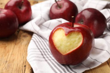 Yüreği oyulmuş kırmızı elma ve ahşap masada diğer meyveler, yakın plan.