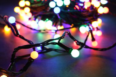 Parlak Noel ışıkları masada, karanlıkta, yakın plan. Yeni yıl tebrik kartı.