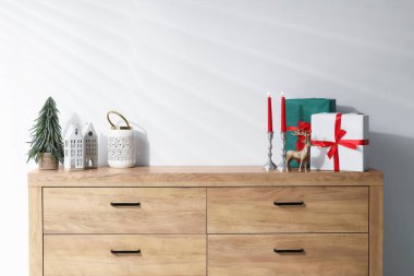 Beyaz duvarın yanındaki ahşap dolapta farklı bir Noel dekoru var.