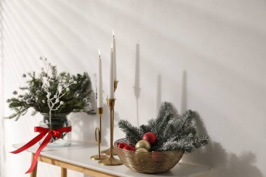 Beyaz duvarın yanındaki konsol masasında farklı bir Noel dekoru, yakın plan.