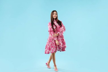 Açık mavi arka planda güzel giyimli bir kadın.